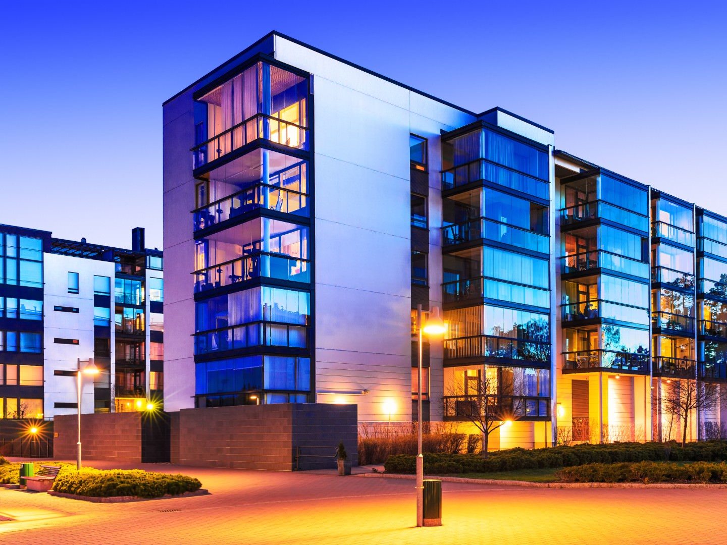 Real Estate Web Design Modern apartment buildings with glowing windows at dusk